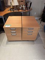 Front view of two rolling file cabinets side by side, showing their top and drawer fronts with silver handles and wheels underneath.