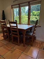 Rectangular farmhouse table with four chairs under window