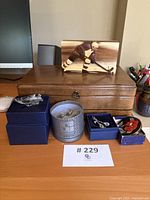 Photo showing wooden jewelry case, multiple blue jewelry boxes with various silver jewelry, and wooden hockey player figurine on desk.