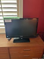 Front view of Toshiba 24-inch TV or monitor turned off, showing black bezel, Toshiba logo, and base stand.