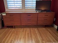 Front view of entire dresser showing nine drawers, integrated handles and overall finish.