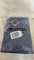 Front view of one navy blue curtain panel folded in plastic packaging with 'deconovo' brand label and barcode visible
