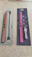 Two rechargeable USB BBQ lighters, one pink, one rose gold, packaged with USB charging cables