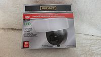 Front view of box showing Defiant motion security light, LED technology, 20W equivalent, battery powered, 400 lumens output, and 180° detection.