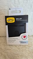 Front view of OtterBox wallet in original packaging showing brand, product type, and features.