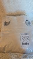 Photo of packaged white velvet curtain panel with metal grommets, label showing brand Nicetown and measurements 52" x 84".