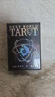 Front view of a new Next World Tarot card deck box showing title and designer details.