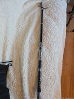 Full view of the telescopic fishing pole extended showing black pole and silver handle.