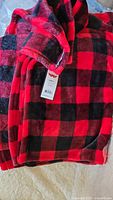 Close-up of folded red and black plaid fleece throw blanket showing pattern and edges.