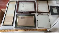 Top view shot of seven different antique picture frames of various sizes and styles on a table with a ruler for scale