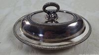 Side view of the silverplate covered dish showing ornate handle on lid and decorative edge