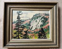 Framed oil painting on board showing landscape scene with rocky cliffs, greenery, and trees.