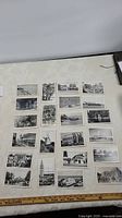 Photo showing the full set of 22 black and white postcards laid out on a table, depicting various urban and natural scenes from the early 1900s.