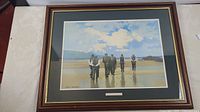 Full view of framed art print showing six men on a beach with sky and water reflecting the figures, signed by John Skelton.