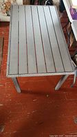 Full top view of gray slatted tabletop and woven wicker edge showing overall size and design.