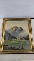 Full view of framed oil painting showing mountainous landscape and gold frame