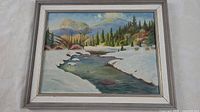 Framed oil painting showing full view of winter landscape with stream, snow, trees, and hills.