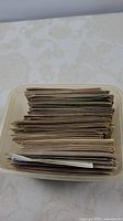 Overhead view of a plastic container filled with many assorted vintage postcards stacked vertically.