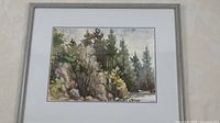 Front view of framed watercolour landscape showing natural forest, rock, and water scene with pine trees.