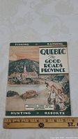 Front cover of the 1933 Quebec tourism booklet titled 'Quebec The Good Roads Province' with illustrated scenic view, ruler for size reference.