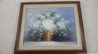Full view of the framed oil painting showing a basket of white flowers with a muted blue-gray background.