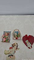 Four vintage Valentine cards placed on a neutral background, showing overall lot contents.