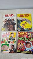 7 MAD magazines from 1980s and 1990s arranged flat on white surface, showing various covers with pop culture parodies and comic art.