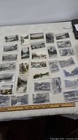 Overview photo showing approximately 30 vintage postcards laid out on a white surface with ruler for scale