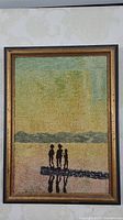 Full view of the woven textile art in frame showing three people on dock at sunset.