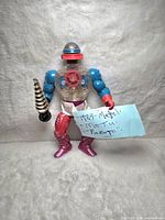 Full view of 1984 Mattel Masters of the Universe Roboto figure showing clear chest with gears, blue arms, red gloves, and drill accessory