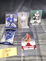 Five limited edition hockey cards placed on black and gray patterned surface with a yellow Lot 6 note. Cards show goalie Jonathan Bernier in blue, Pekka Rinne jersey card with patch, Max Domi and another goalie.