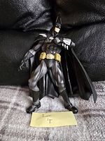 Batman 7 inch figure standing on fabric surface with black leather backdrop.