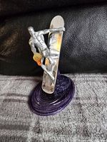 Front view of Silver Surfer die cast figurine surfing on its board mounted on a purple cosmic wave base.
