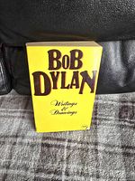 Front cover of the Bob Dylan book with yellow background and large brown text for the title.
