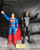 Two 12-inch action figures of Superman and Cyborg posed standing on a black and grey background with a 'Lot 7' label beneath them.