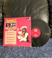 Front cover of the vinyl record with red background and man in a sombrero playing guitar, record partially out of sleeve.