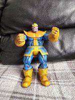 Front view of the blue and gold armored Thanos action figure standing on a surface with a dark background