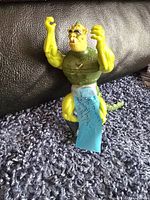 Front view of the 1983 Masters of the Universe Whiplash figure standing on a carpet with a note taped to it.