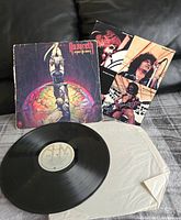 Vinyl record, cover and insert laid out on a black surface showing rough cover and record condition.