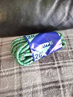 Image showing coiled green braided rope with red and white accents, wrapped with paper label indicating '20 ft' and 'rope'