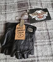 Top view of black leather fingerless gloves with Harley Davidson tag and handwritten size small label.