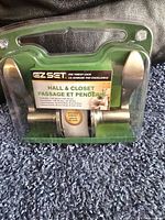 EZ Set hall and closet door lever set in original sealed packaging placed on carpeted floor.