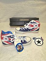Pair of Converse Chuck Taylor All-Star Hi shoes with Union Jack and blue/red/white colors, original Converse box behind them, 'The Who' tag attached to laces visible