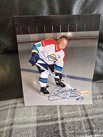 Full view of Bobby Hull in hockey uniform on ice with autograph visible
