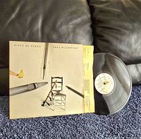 Front cover of Paul McCartney Pipes of Peace vinyl record showing minimalist art design with chair and pipes.