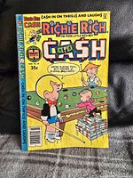 Front cover of Richie Rich comic issue 28 with colorful illustration of Richie Rich playing pool with money.