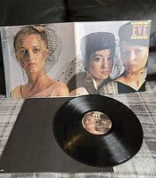 Photo showing the front cover of the 'Eve' album by The Alan Parsons Project and the vinyl record lying in front of it.