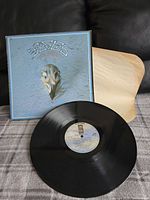 Full view of the vinyl record with the album cover visible and inner paper sleeve beside it.