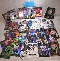 Photo showing an assortment of NHL hockey trading cards from various teams, some cards holographic and from different series including Panini, Upper Deck, and Parkhurst