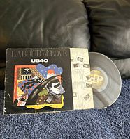 Labour of Love UB40 clear vinyl record partially out of sleeve on couch background to show condition of record and sleeve